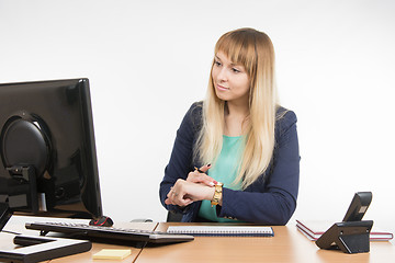 Image showing Business woman checks the time on a computer with a wristwatch