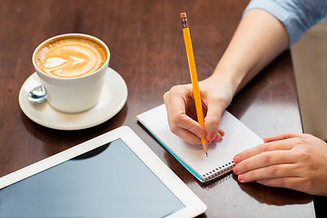 Image showing close up of woman writing to notebook with pencil