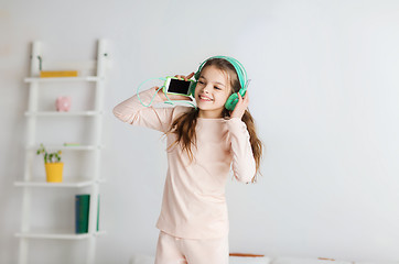 Image showing girl jumping on bed with smartphone and headphones