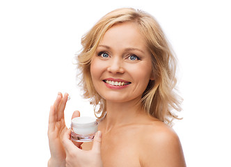 Image showing happy woman applying cream to her face