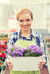 Image showing happy woman holding flowers in greenhouse