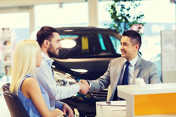 Image showing happy couple with car dealer in auto show or salon