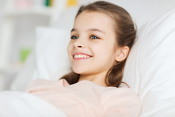 Image showing happy smiling girl lying awake in bed at home