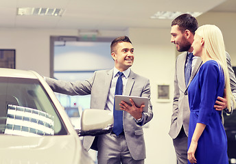 Image showing happy couple with car dealer in auto show or salon