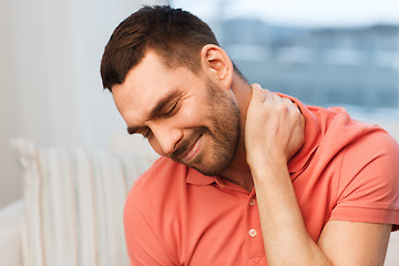 Image showing unhappy man suffering from neck pain at home