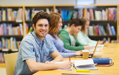 Image showing happy student boy with books writing in library