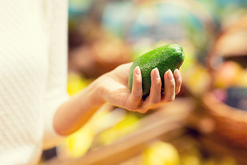 Image showing close up of woman hand holding avocado in market