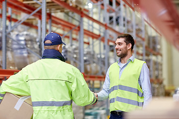 Image showing men in safety vests shaking hands at warehouse