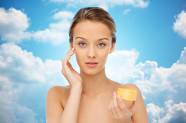 Image showing young woman applying cream to her face