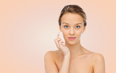 Image showing young woman applying cream to her face