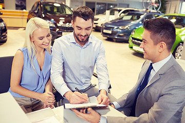 Image showing happy couple with car dealer in auto show or salon