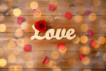 Image showing close up of word love cutout with red rose on wood