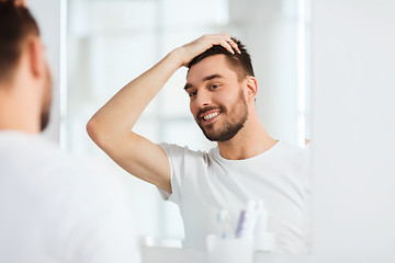 Image showing happy young man looking to mirror at home bathroom