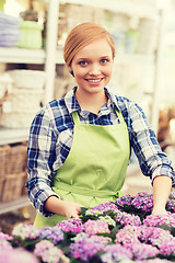 Image showing happy woman taking care of flowers in greenhouse