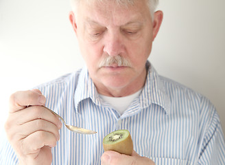 Image showing Senior prepares to eat kiwifruit.  