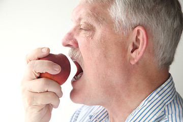 Image showing Older man eating fresh peach	