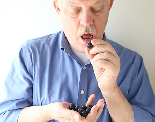 Image showing Senior man eating blueberries