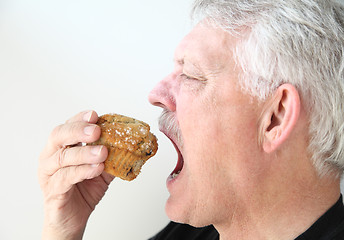 Image showing Man eats blueberry muffin 
