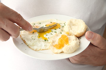 Image showing Man cutting into fried eggs 