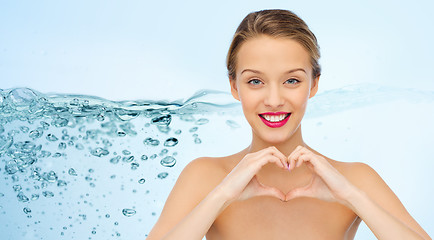 Image showing smiling young woman showing heart shape hand sign