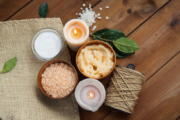 Image showing close up of natural body scrub and candles on wood