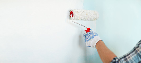 Image showing close up of male in gloves painting wall