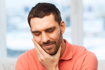 Image showing unhappy man suffering toothache at home