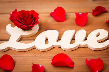 Image showing close up of word love cutout with red rose on wood