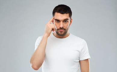 Image showing man with finger at temple over gray background