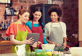 Image showing happy women with tablet pc cooking in kitchen