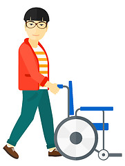 Image showing Man pushing wheelchair.