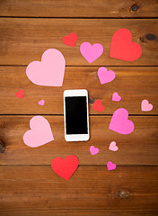 Image showing close up of smartphone and hearts on wood