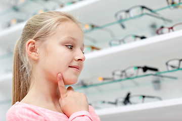 Image showing little girl choosing glasses at optics store