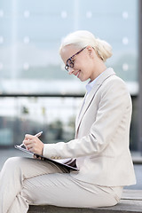 Image showing young smiling businesswoman with notepad outdoors