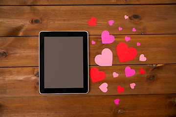 Image showing close up of tablet pc and hearts on wood