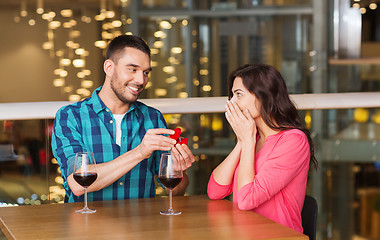 Image showing man giving engagement ring to woman at restaurant