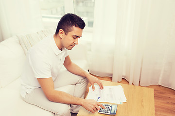 Image showing man with papers and calculator at home