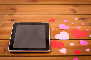 Image showing close up of tablet pc and hearts on wood