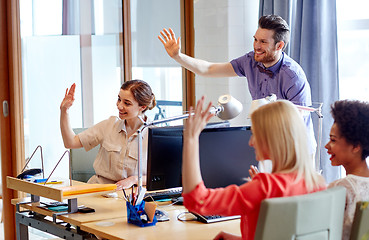 Image showing happy creative team waving hands in office