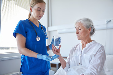 Image showing nurse giving medicine to senior woman at hospital