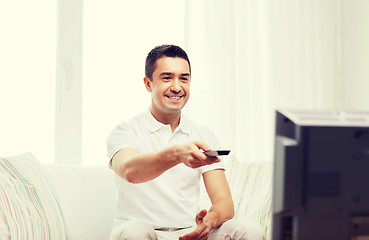 Image showing smiling man with remote control watching tv
