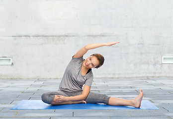 Image showing happy woman making yoga and stretching on mat