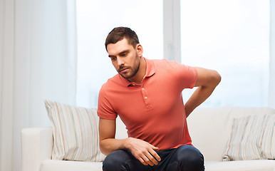 Image showing unhappy man suffering from backache at home