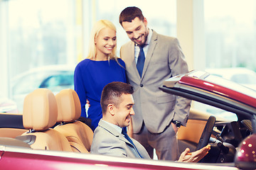 Image showing happy couple with car dealer in auto show or salon