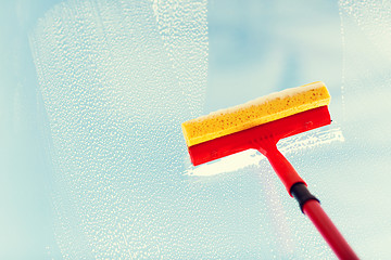 Image showing close up of hand cleaning window with sponge