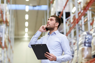 Image showing man with clipboard and smartphone at warehouse