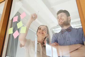 Image showing happy creative team writing on blank office glass