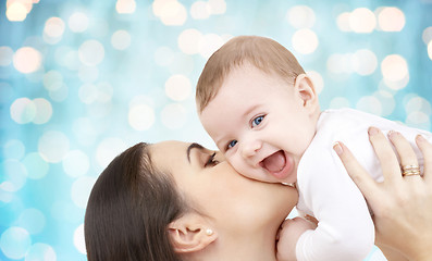 Image showing happy mother kissing her baby over blue lights