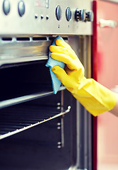 Image showing close up of woman cleaning oven at home kitchen