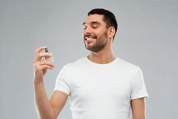 Image showing smiling man with male perfume over gray background